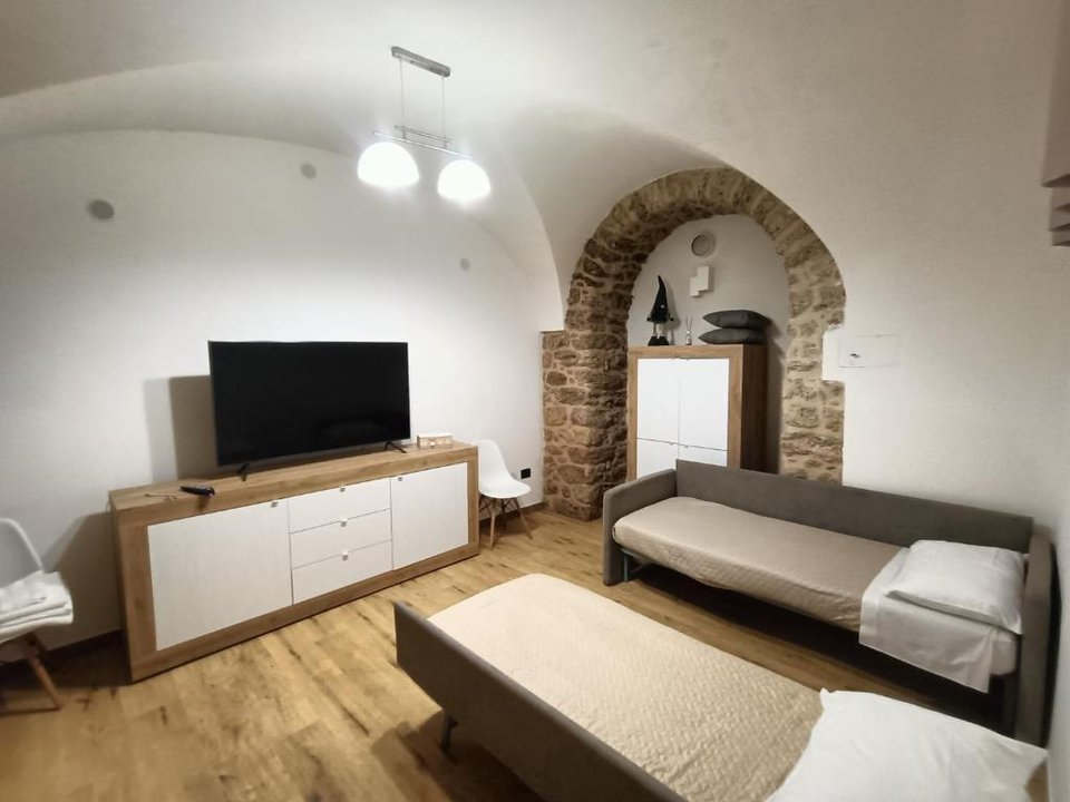 Camera con TV, letti singoli e arco in pietra a vista - alloggio Subiaco